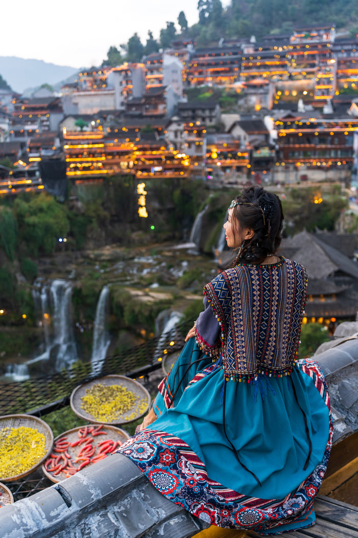 Mujer china mirando a la ciudad de Lijiang al anochecer
